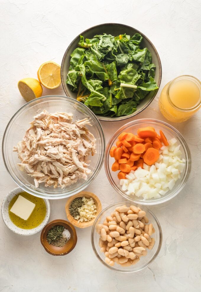 Chicken, carrots, onion, white beans, chard, lemon, broth, and seasoning in prep bowls.