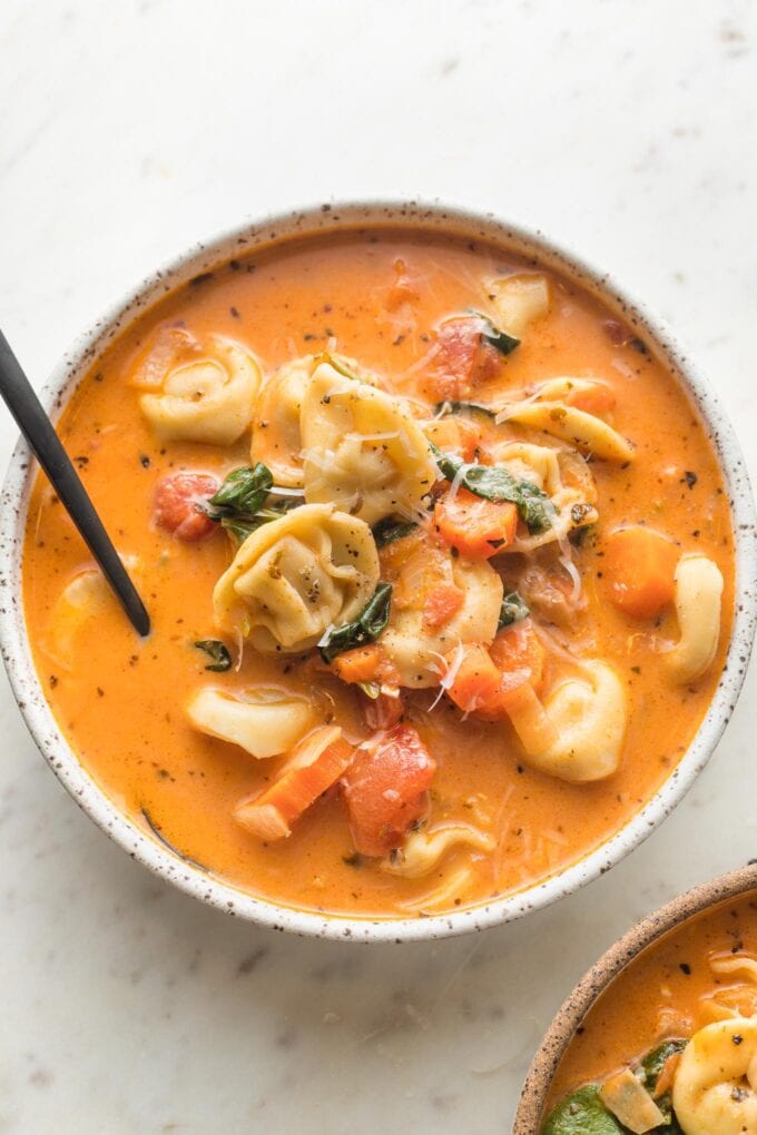 White bowl of creamy tomato tortellini soup.