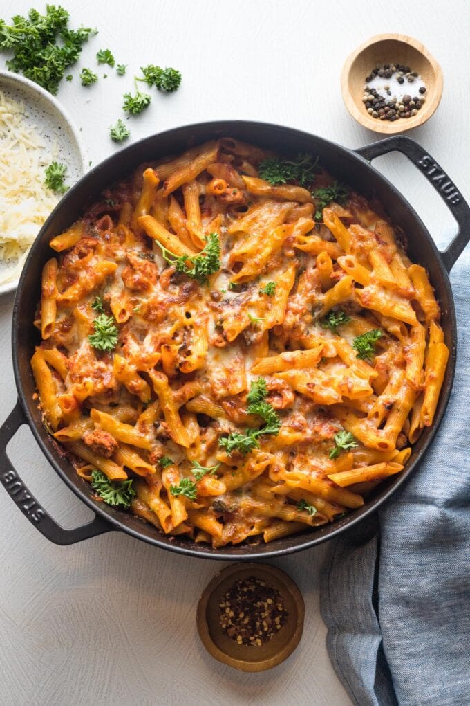 A ground turkey pasta bake, fresh out of the oven and ready to serve with fresh herbs and extra red pepper flakes.