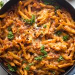 A large cast iron dish holding a baked ground turkey pasta dish right out of the oven.