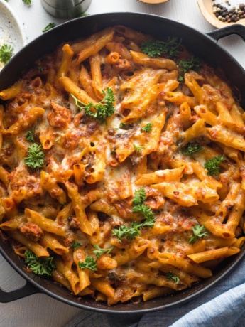 A large cast iron dish holding a baked ground turkey pasta dish right out of the oven.