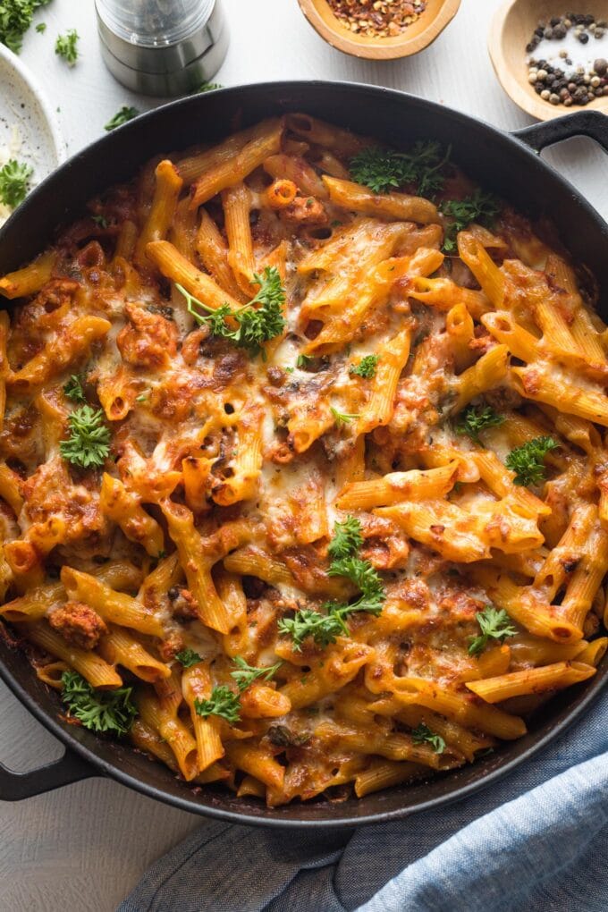 A large cast iron dish holding a baked ground turkey pasta dish right out of the oven.