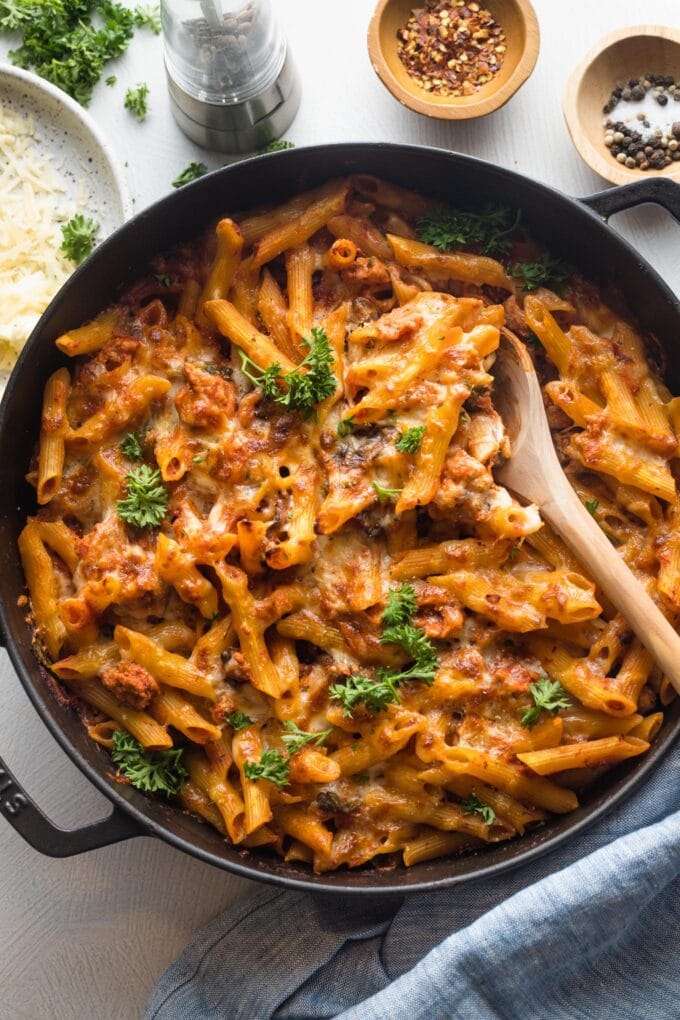 A serving spoon scooping out heaping portions of a baked ground turkey pasta.