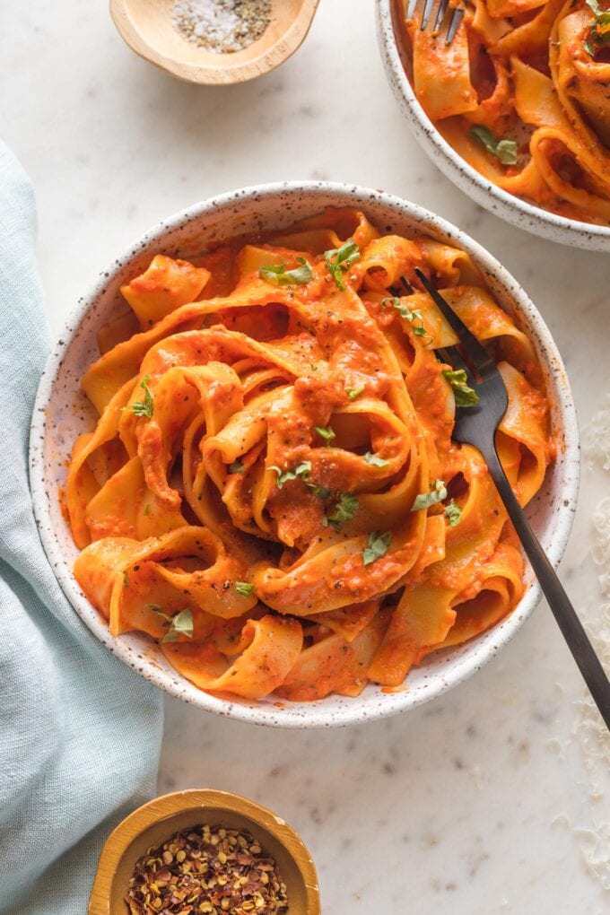 Small bowl of creamy roasted red pepper pasta with Parmesan and red pepper flakes.