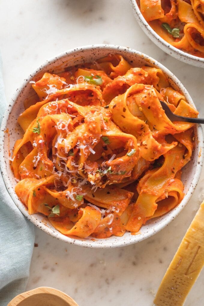 Close-up of wide ribbons of pappardelle coated with a creamy roasted red pepper pasta sauce.