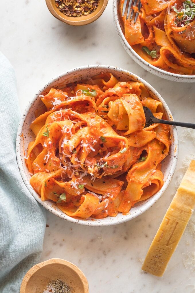 Two bowls of pappardelle with a creamy roasted red pepper sauce.