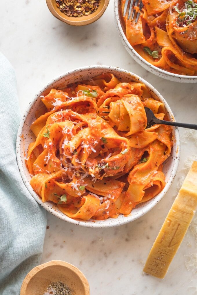 Two bowls of pappardelle with a creamy roasted red pepper sauce.