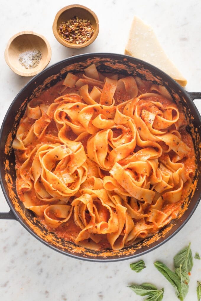 Roasted red pepper pasta sauce coating pappardelle in a large skillet.