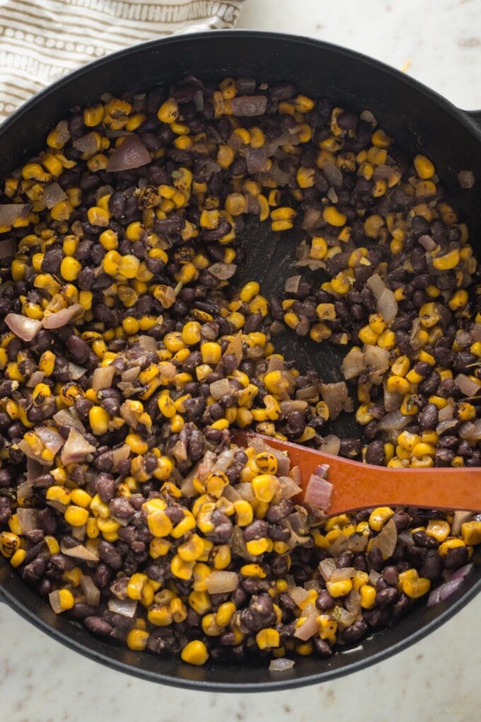 Seasoned black bean and corn enchilada filling in a cast iron skillet.