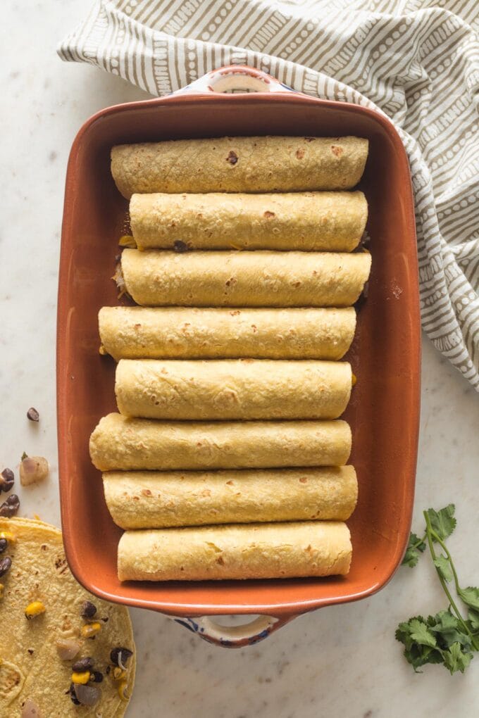 Baking dish filled with rolled tortillas.