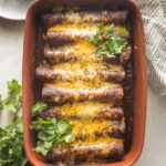 Brown ceramic baking dish filled with black bean and corn enchiladas fresh out of the oven.