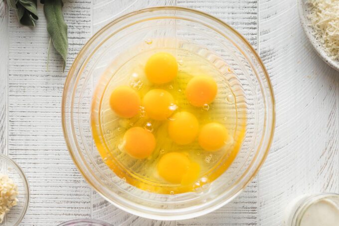 Eggs cracked into a clear mixing bowl.