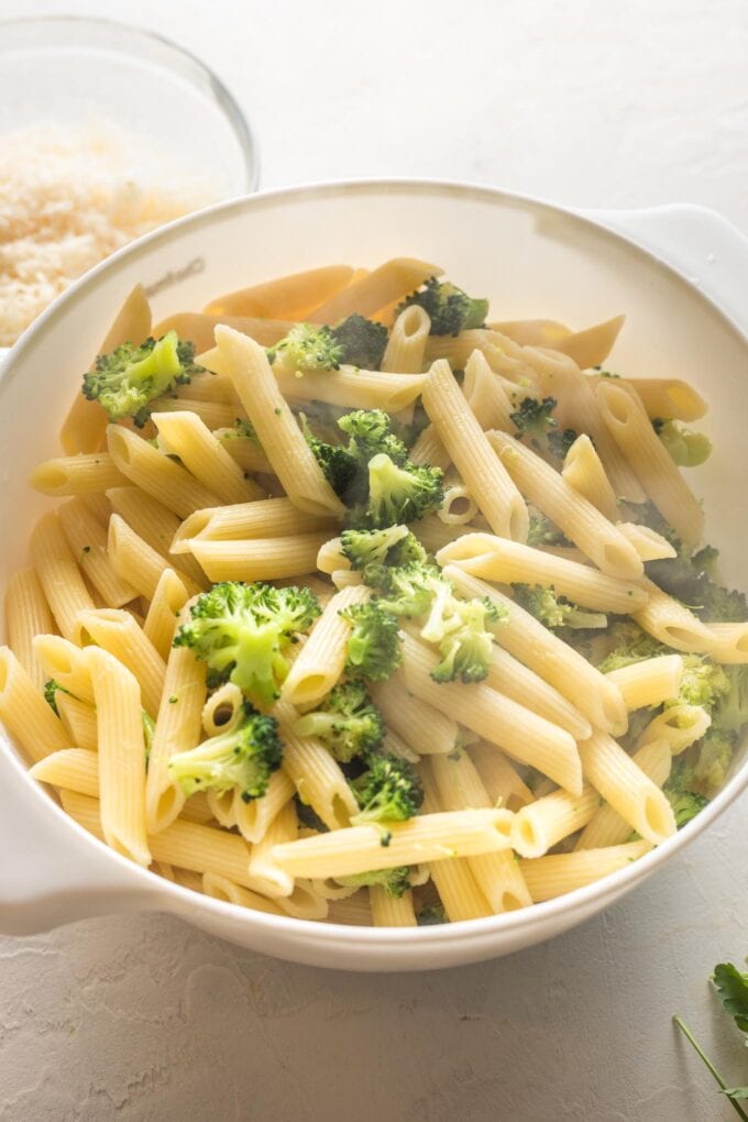 Penne and finely chopped broccoli florets cooling together in a colander.