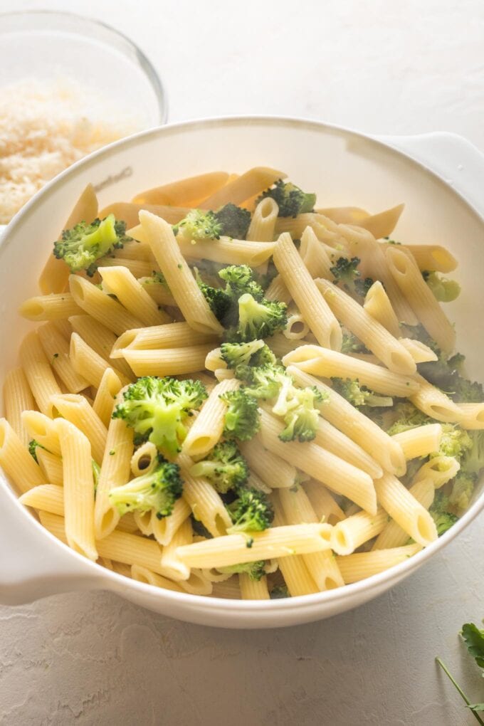 Penne and finely chopped broccoli florets cooling together in a colander.