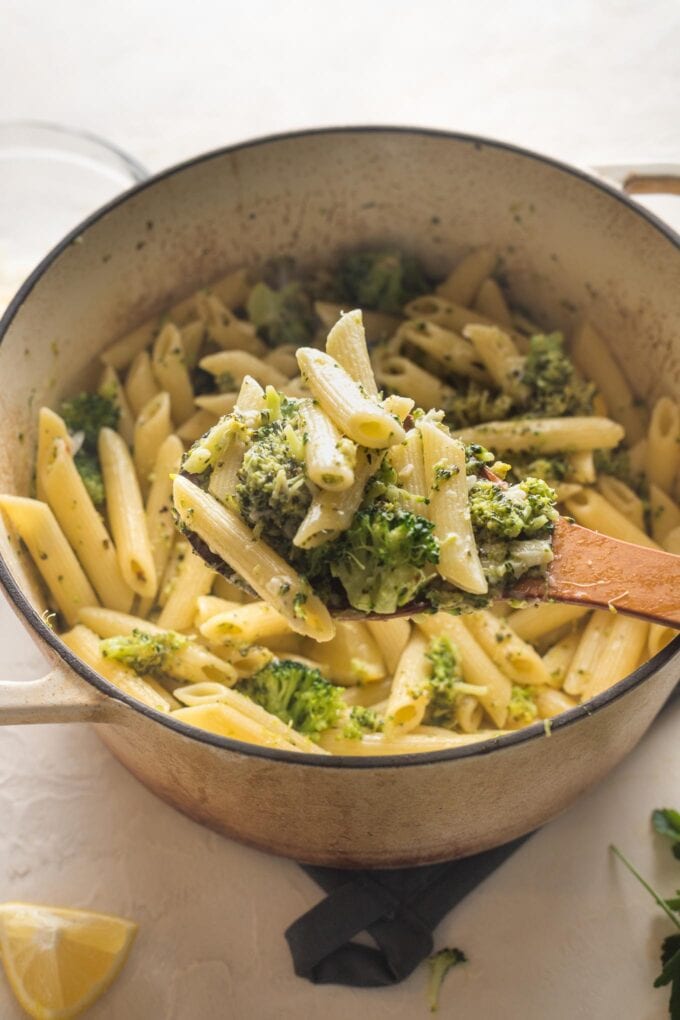 Close up of a serving spoon lifting out a scoop of piping hot lemon broccoli pasta.