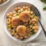 Small plate of sesame spiced chicken meatballs served on top of a chickpea salad.