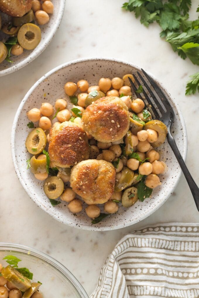 Small plate of sesame spiced chicken meatballs served on top of a chickpea salad.