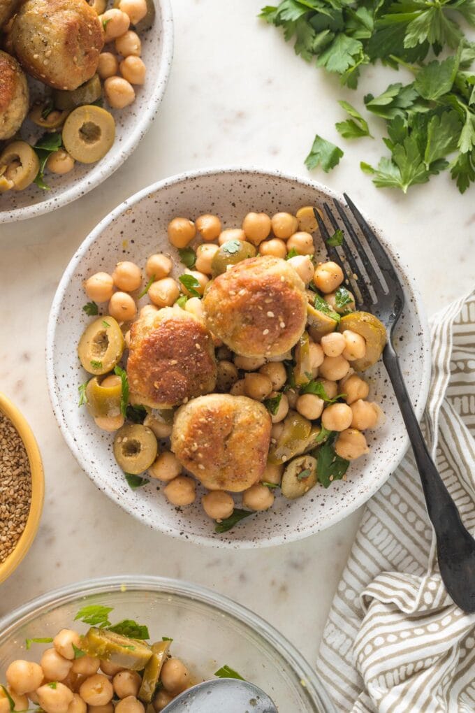 Small plate of sesame spiced chicken meatballs served on top of a chickpea salad.