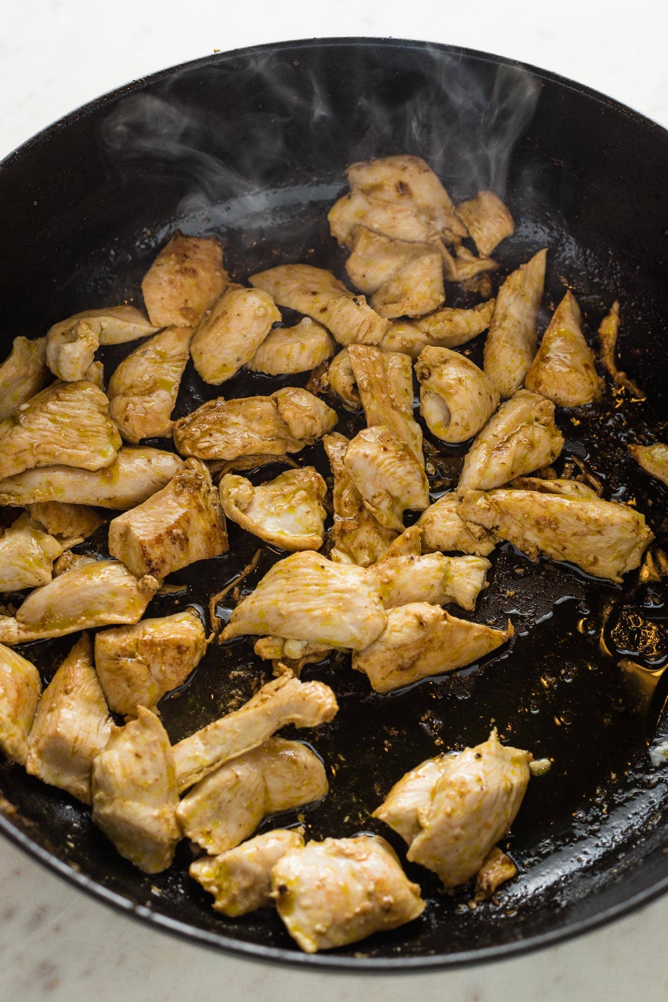 Thinly-sliced chicken, browned in a skillet.