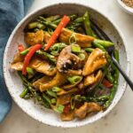 White bowl with a serving of chicken asparagus stir fry ready to eat.