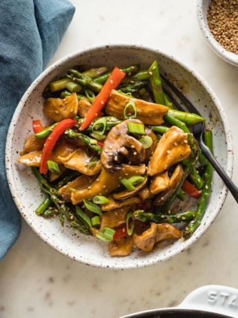 White bowl with a serving of chicken asparagus stir fry ready to eat.