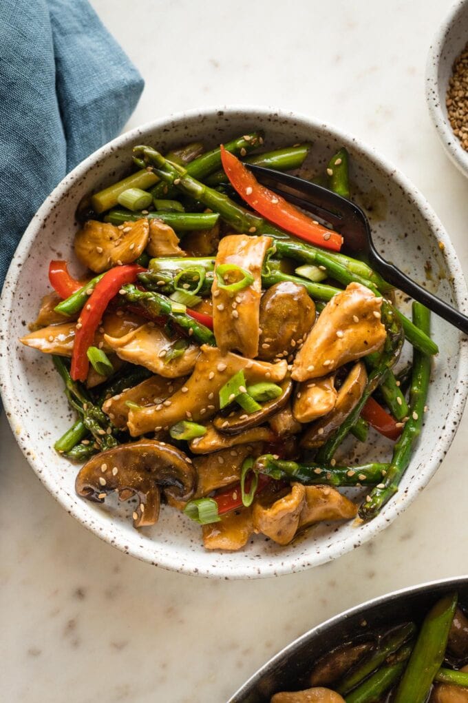 White bowl with a serving of chicken asparagus stir fry ready to eat.