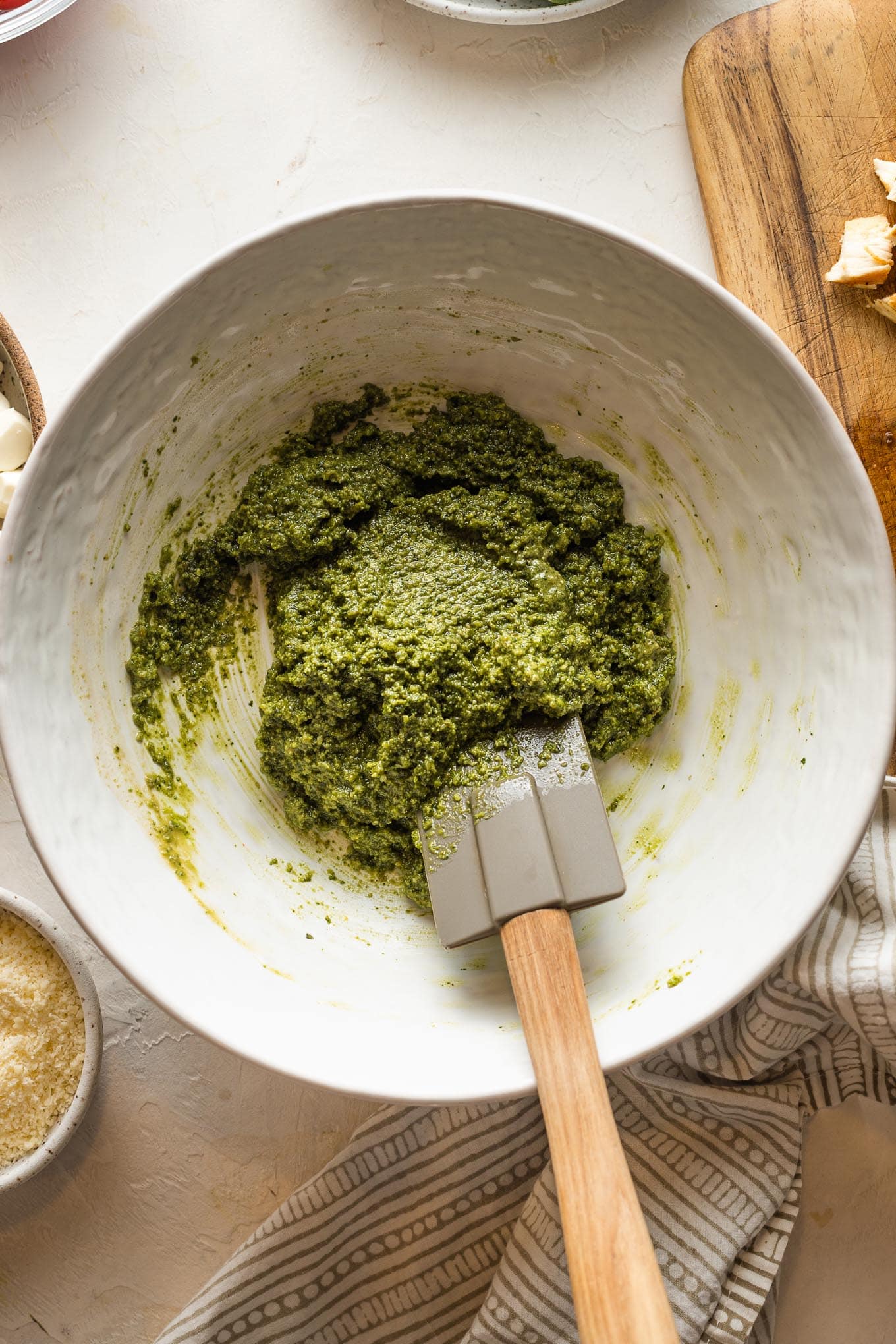 Pesto and red wine vinegar mixed together in a large white bowl.