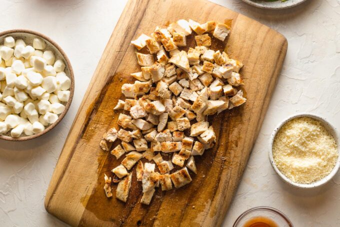 Grilled chicken on a cutting board, cut into bite-sized pieces.