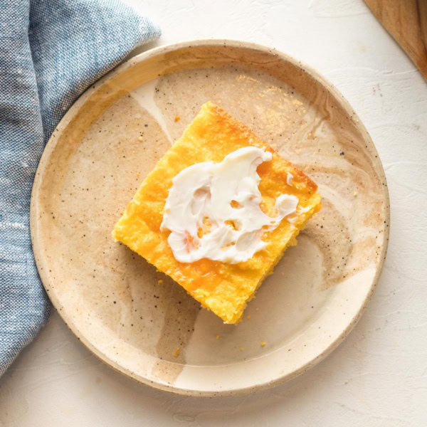 Slice of buttermilk cornbread with cheddar cheese, served with a slather of butter.