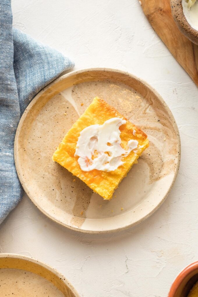 Slice of buttermilk cornbread with cheddar cheese, served with a slather of butter.