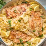 Skillet full of lemon chicken pasta in a light citrus sauce, garnished with lemon wedges and fresh Italian parsley.