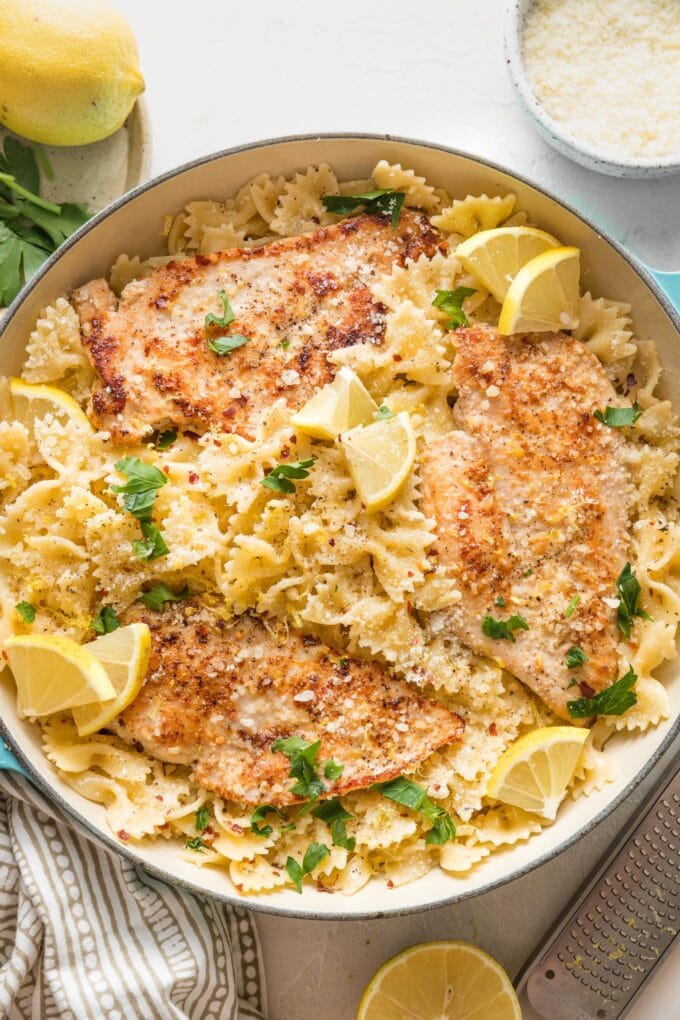 Skillet full of lemon chicken pasta in a light citrus sauce, garnished with lemon wedges and fresh Italian parsley.