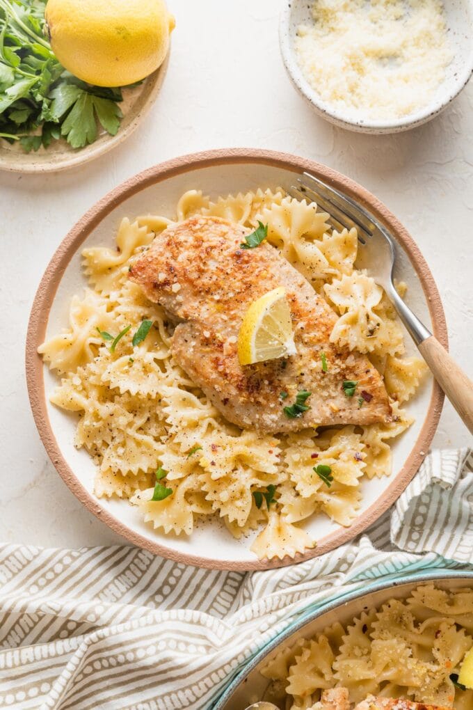 Small pasta bowl filled with a helping of lemon chicken pasta, with a fork poised to dig in.