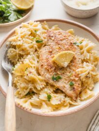 Angled view of a shallow bowl holding a generous portion of lemon chicken pasta in a light sauce.