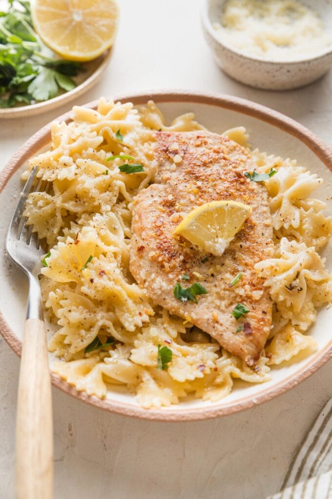 Angled view of a shallow bowl holding a generous portion of lemon chicken pasta in a light sauce.