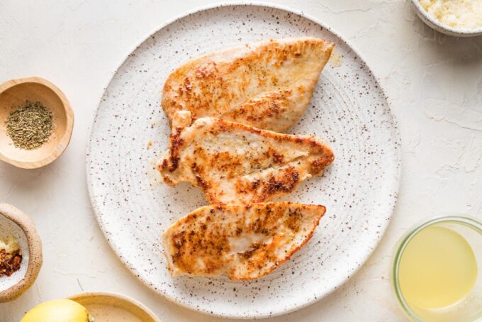 White plate with browned chicken breasts resting on it.