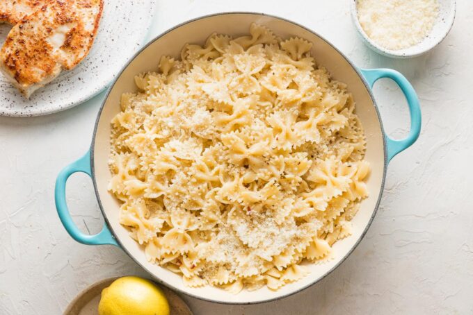 Pasta scattered with Parmesan in a low skillet.