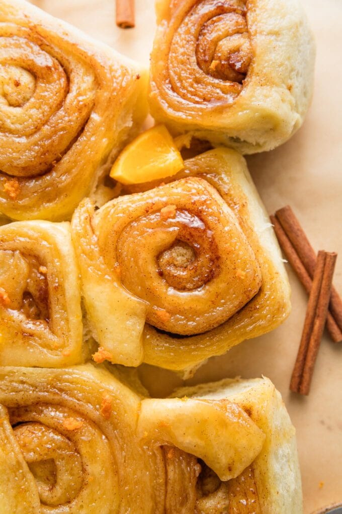 Close up of glazed orange sweet rolls with cinnamon sugar.