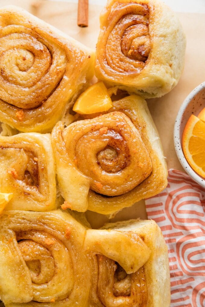 Orange sweet rolls garnished with orange wedges and zest.