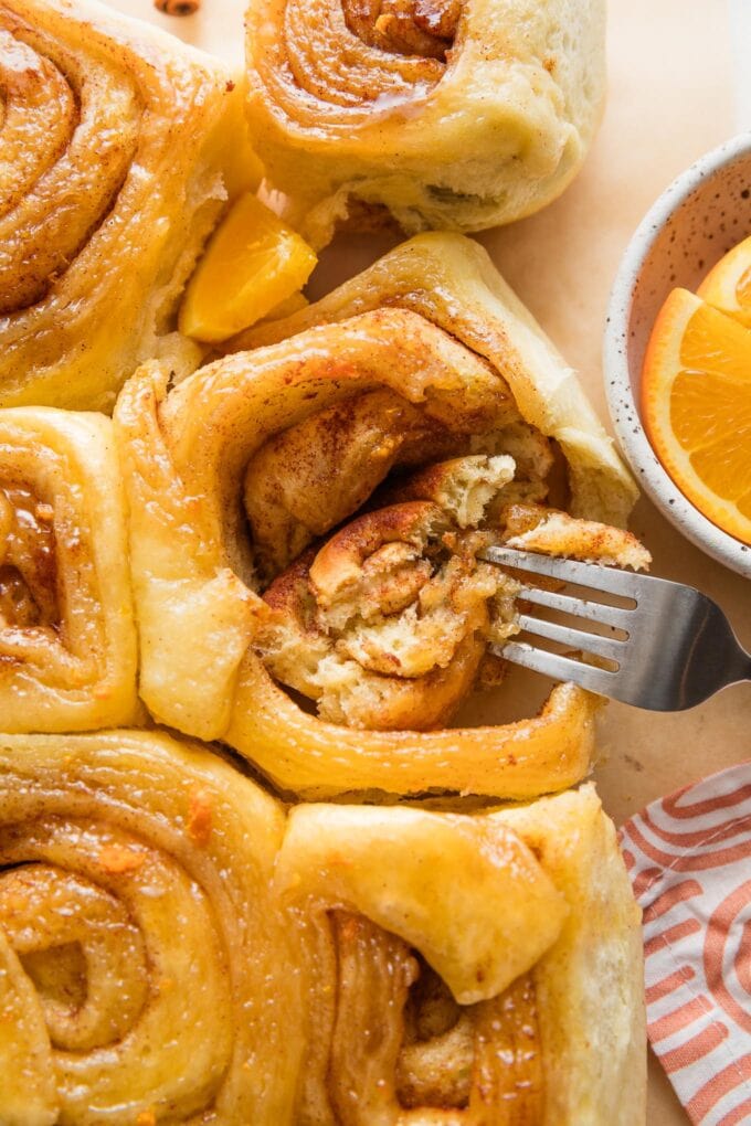 Fork pulling apart the tender inside of an orange sweet roll.