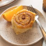 Close up of a homemade glazed orange sweet roll.