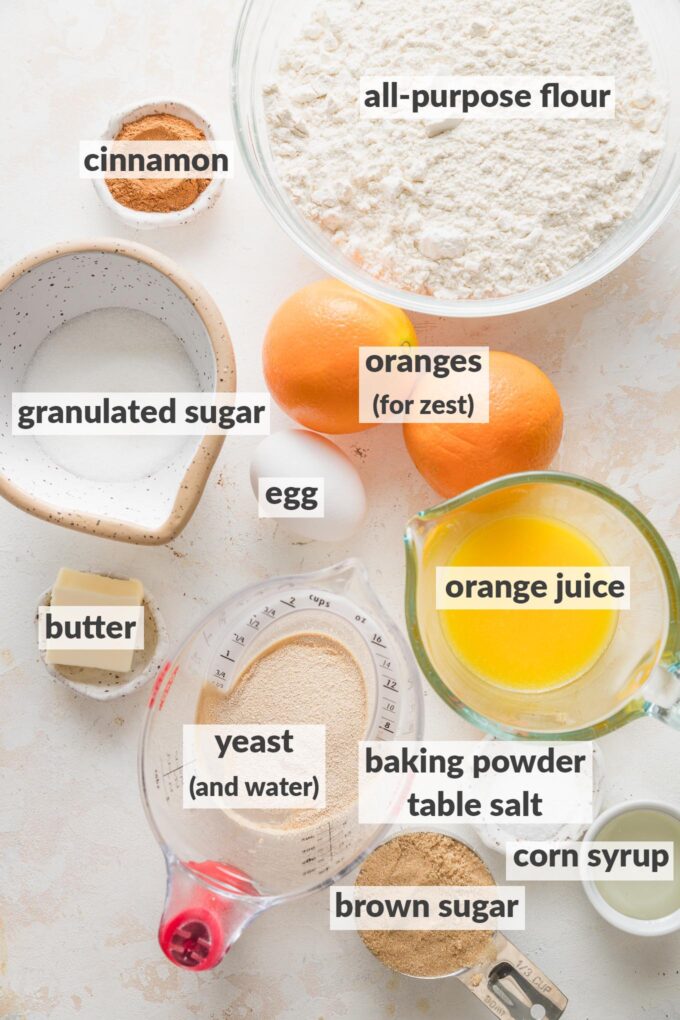 Labeled overhead photo of the ingredients for glazed orange rolls, measured into prep bowls and ready to bake.