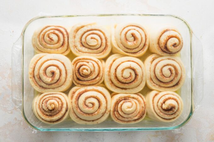 Puffy orange rolls filling out a large 9x13-inch baking pan.