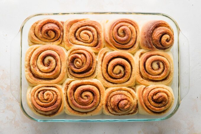 Orange cinnamon sweet rolls just baked in a 9x13-inch pan, golden brown on top.