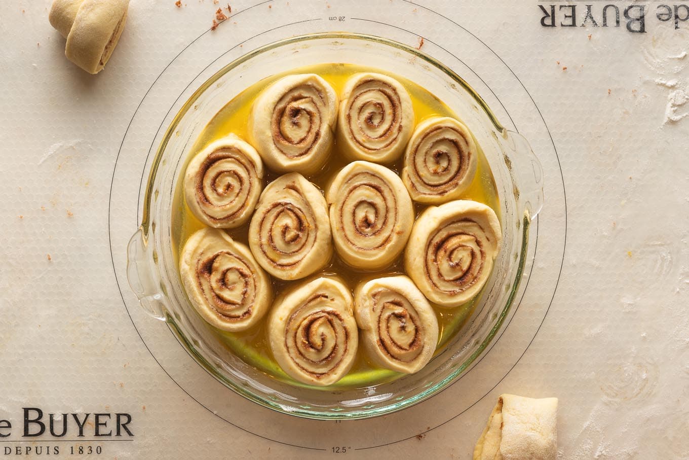 Pie plate with sliced orange rolls ready for their second rise.