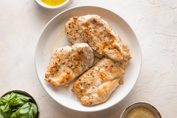 Browned chicken breasts resting on a plate.