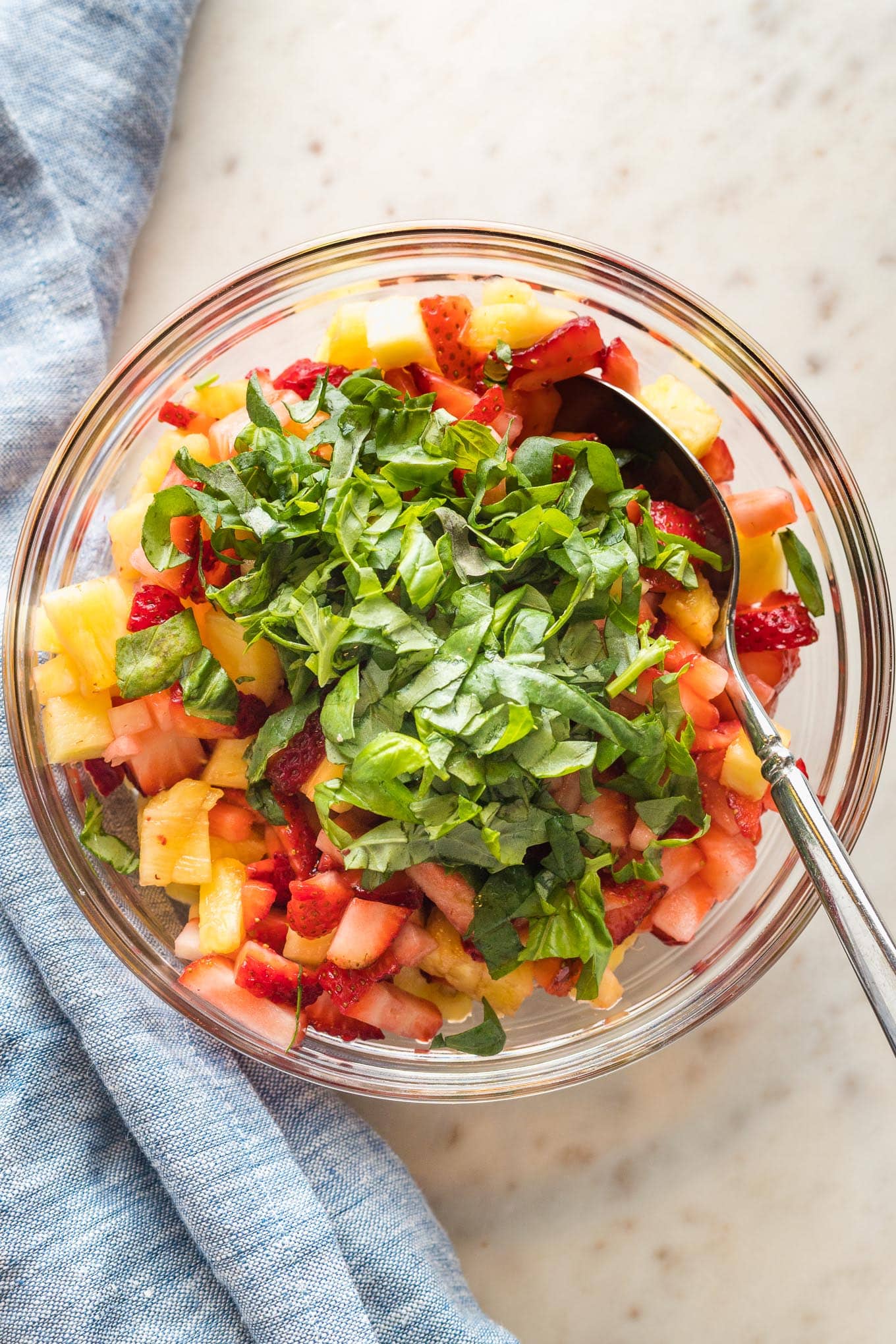 Slivered basil and balsamic vinegar sprinkled on top of diced strawberries and pineapple.