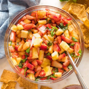 Serving bowl filled with sweet balsamic strawberry pineapple salsa, served with cinnamon churro chips.