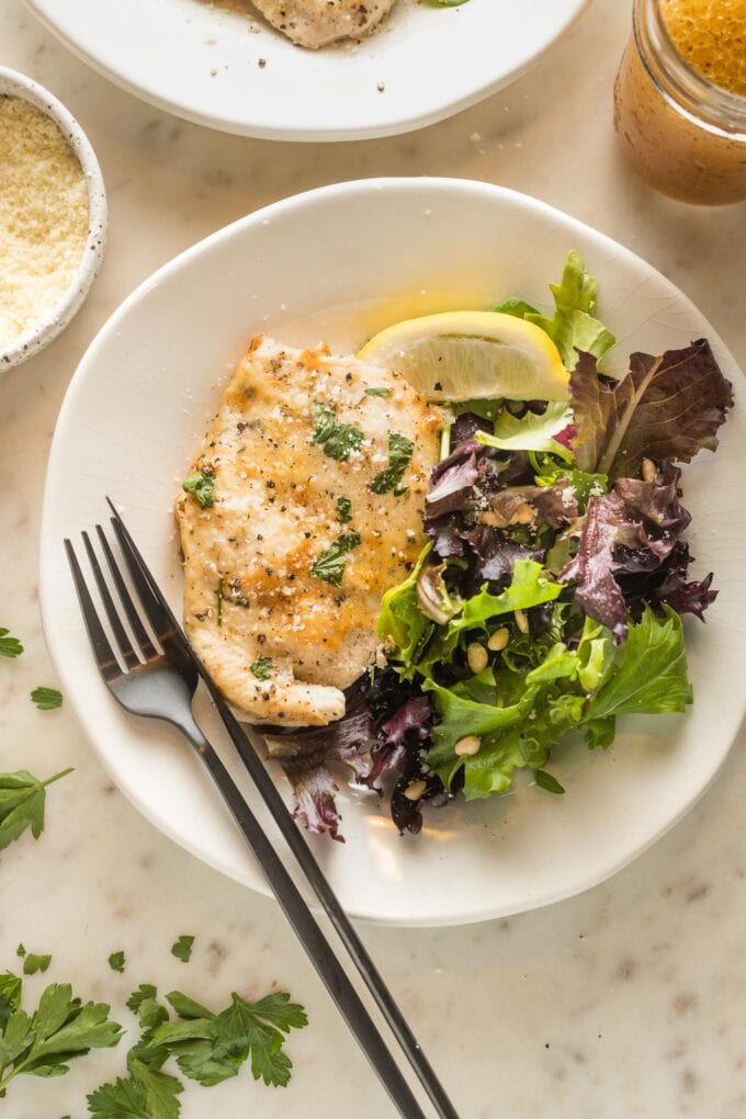 Plate with Italian dressing chicken served with a green salad.