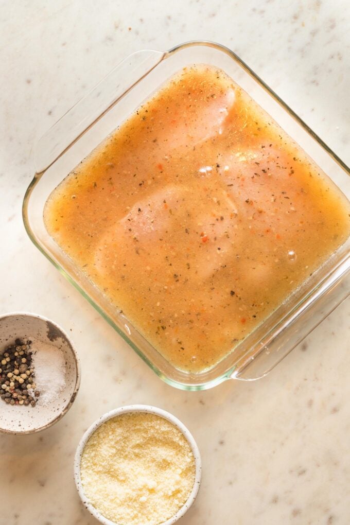 Salad dressing poured over chicken breasts in a baking dish.